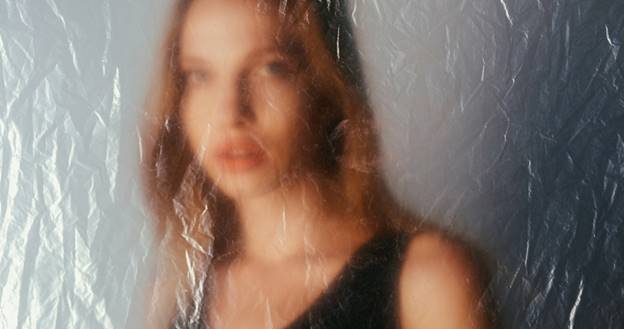 A blurred portrait of a fair-skinned woman looking through textured plastic. This image accompanies website content, possibly about storing evidence.
